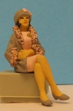 Omen - Seated woman with crossed legs, wearing a fur-trimmed coat