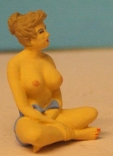 Omen - Girl, topless, sitting cross-legged on the ground
